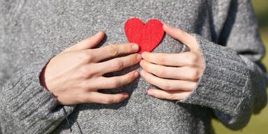 En kvinna håller i ett rött hjärt. Svenska forskare har tagit fram en ny metod för att mäta risken att drabbas av hjärtsjukdom