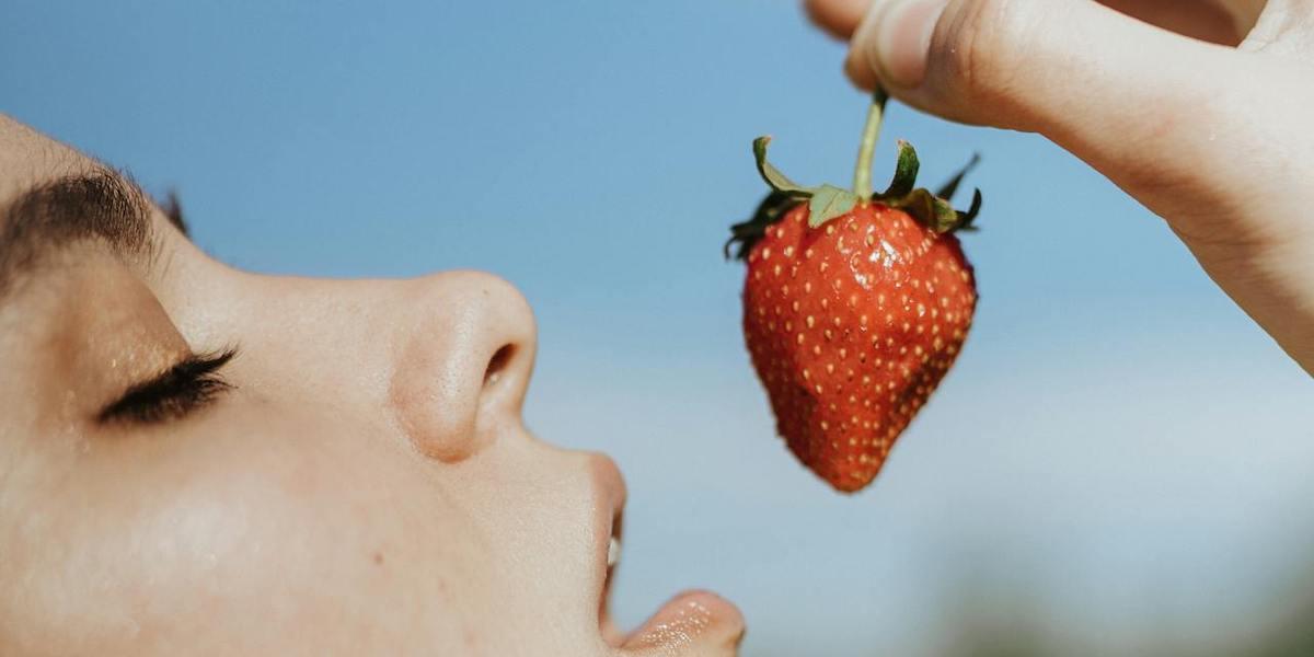En kvinna stoppar en jordgubbe i munnen. Visst älskar vi jordgubbar, men ibland håller de ganska dåligt och möglar innan vi hunnit äta upp dem. Här är några tips på hur du kan få dem att hålla sig fräscha lite längre