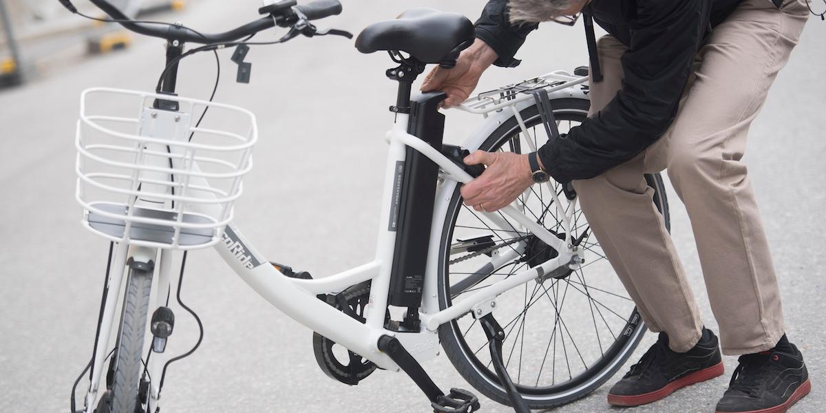 En man tar bort det löstagbara batteriet från ramen på sin elcykel.