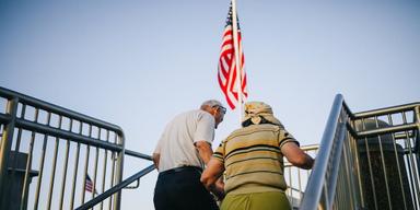 Ett äldra par går uppför en trappa med USA:s flagga i bakgrunden. Amerikaners medellivslängd är 77,5 år och amerikaner födda från 1960 får full pension vid 67, därför planerar inte många för en lång pension