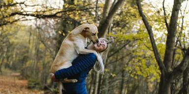 En kvinna kramar en stor hund som hon håller i famnen. Allt fler amerikaner har husdjur. Hundar är de mest populära husdjuren och i USA finns det en hund i 65,1 miljoner hushåll, eller 44,5 procent.