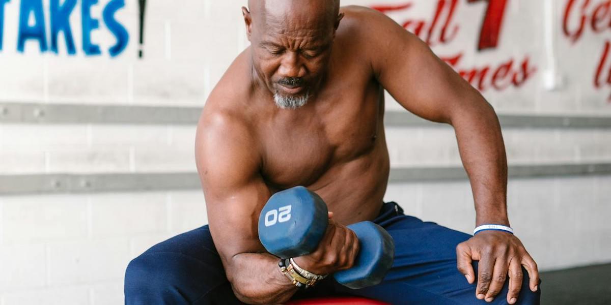 En man styrketränar med en hantel. En 95-årig man från New Hampshire styrketränar på gymmet fyra dagar i veckan, han tror att det är en av anledningarna till att han är frisk. Mannen på bilden är inte mannen i texten