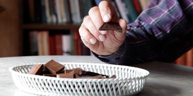 En man äter choklad. Vilken choklad vi gillar påverkas av vilken choklad våra politiska motståndare gillar, det visar en studie.