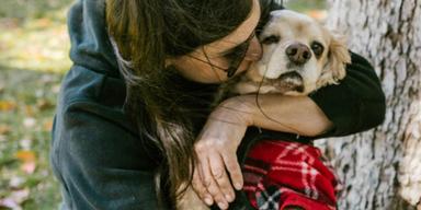 En kvinna kramar och pussar en hund. Sorgen när ett älskat husdjur dör är stor och svår, men det finns saker som kan hjälpa dig i sorgeprocessen