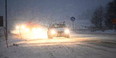 En bil kör i snöfall. På fredagen varnar SMHI för oväder med snö i kombination med vind och snöovädret har redan skapat stora problem i trafiken.