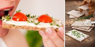 En kvinna äter knäckebröd och ljust knäckebröd på ett bord.