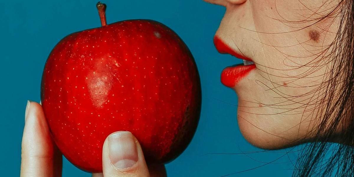 En kvinna ska ta en tygga av ett stort rött äpple. En expert reder ut om det verkligen är bra för magen att äta ett äpple om dagen