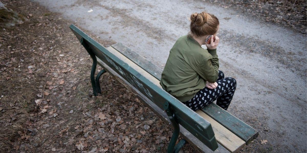 Kvinna på bänk med mobiltelefon