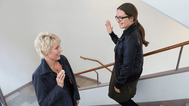 Två bekanta som hälsar på varandra i en trappa.